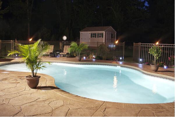 Light brown stamped concrete swimming pool patio deck at night