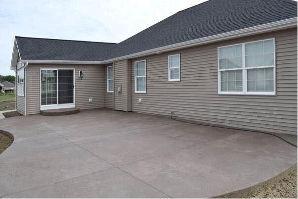 Smooth grey concrete patio slab with organic shape on new home construction